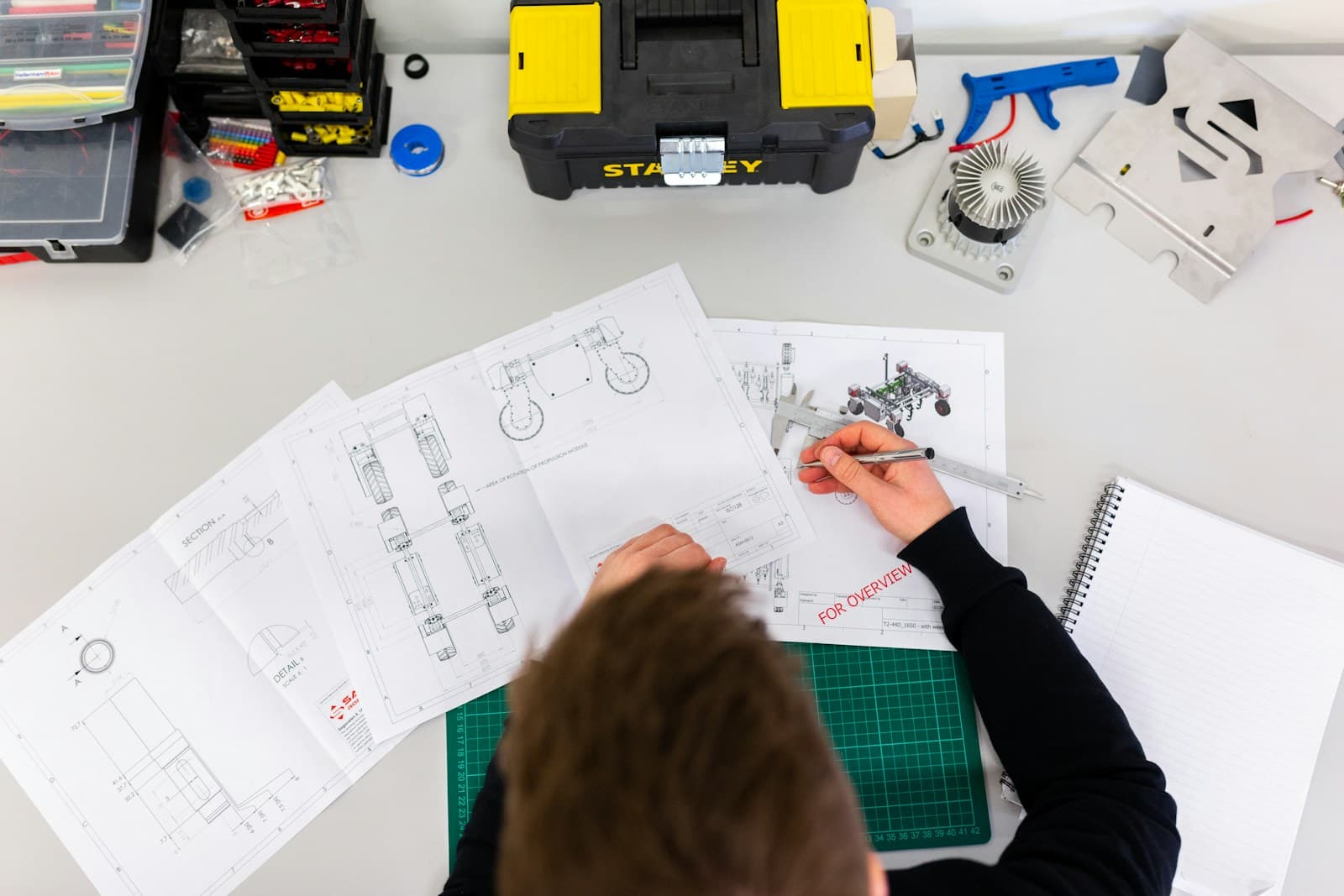 Engineer reviewing technical drawings and a prototype assembly